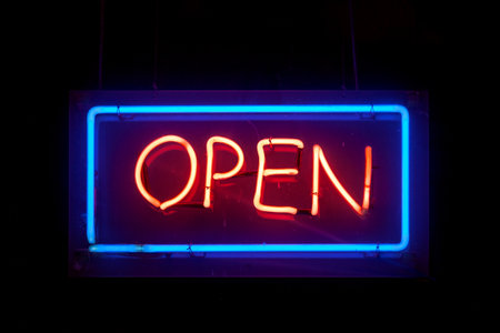 Close-up on a neon light shaped into a blue rectangle and the word "open" in red.の写真素材