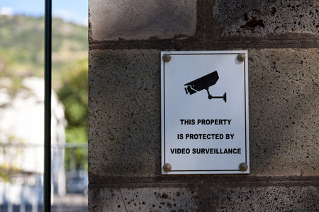 White sign on a stone pillar saying "This property is protected by video surveillance".の写真素材