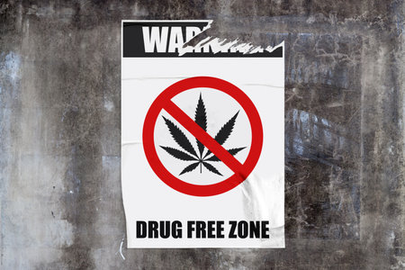 Full-frame weathered concrete wall with a torn white poster in the middle depicting a marijuana forbidden sign with the message "Warning - Drug free zone" written around.の写真素材