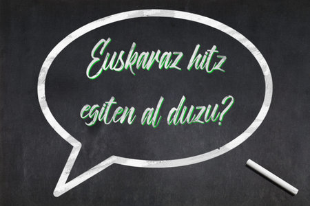 Blackboard with a bubble drawn in the middle with the short phrase in Basque Parli corsu?, meaning...