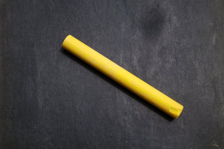 Close up on a yellow chalk stick on a blackboard.の写真素材