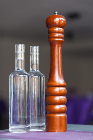 Set of two bottles of water and a pepper grinder on a table.