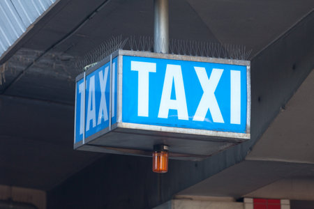 Close-up on a blue Taxi pick up sign outside a train stationの写真素材