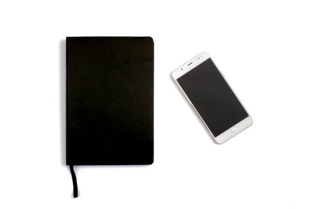 A black leather notebook by the side of a white unmarked smartphone on a white background.の写真素材