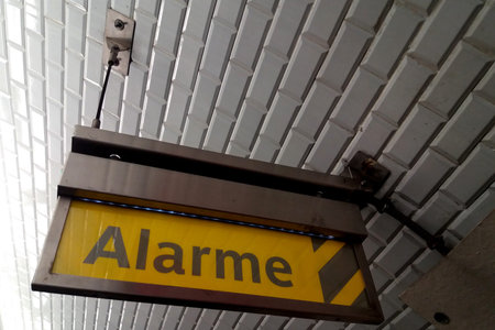 Close-up on a yellow alarm sign written in French in the Paris Metro.