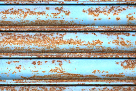Full frame close-up on a rusty cyan iron shutter.