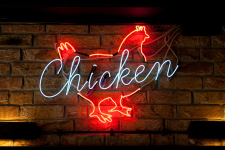 Close-up on a neon light shaped into a chicken with written in it "Chicken".の写真素材