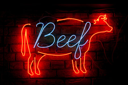 Close-up on a neon light shaped into a cow with written in int "Beef".の写真素材