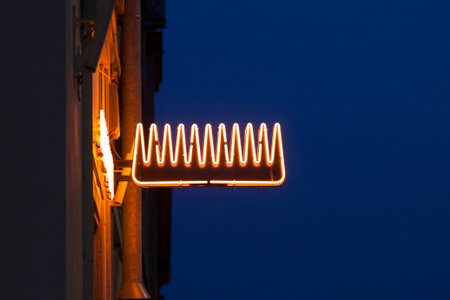 Close-up on a neon light shaped into a comb above a Hairdresser.の写真素材