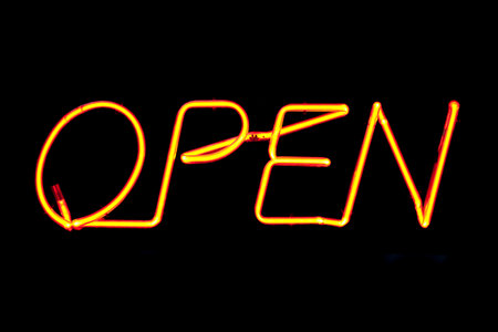 An orange neon sign inside the window of an Irish Pub saying "Open".の写真素材