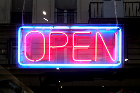 Close-up on a neon light shaped into a blue rectangle and the word "open" in red.の写真素材