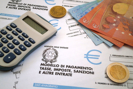 A calculator and some euro coins and banknotes on the top of an Italian tax form (Mod. F23).の写真素材