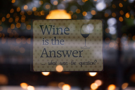Sign in the window of a bar saying "Wine is the answerâ¦ What was the question?".の写真素材