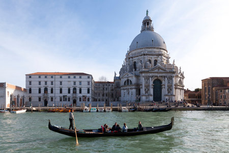 Venice, Italy - March 07 2019: Boatman driving a gondola filled with tourists opposite Basilica of Santa Maria della Salute.のeditorial素材