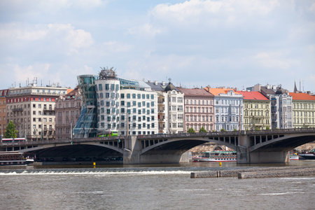 Prague, Czech Republic - June 16 2018: The JirÃ¡sek Bridge crossing the Vltava River with behind, the Dancing House (Czech: TanÄÃ­cÃ­ dÅ¯m), a curving modern office block by architect Frank Gehry, with top-floor restaurant offering city views.のeditorial素材