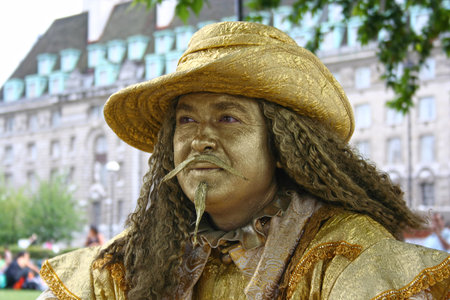 London, England - August 19 2006: A Street artist in golden âMusketeerâ costume playing the human statue on the Thames riverbank near London Eye.のeditorial素材