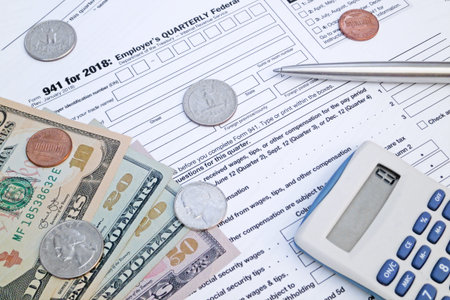 A calculator, a pen and some US dollar coins and banknotes on the top of a Employer's Quarterly...