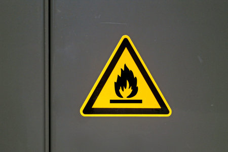 Yellow caution sign on a metal door warning about "Flammable".の写真素材