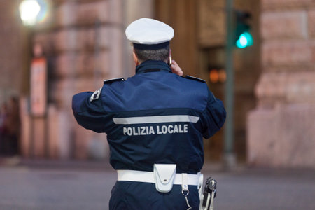 Genoa, Italy - March 30 2019: Officer of the "Polizia locale" (English: Local police) talking on phone while doing the traffic.のeditorial素材