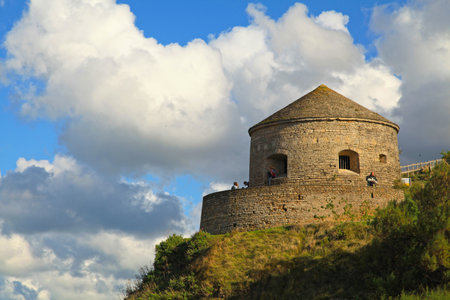 Port-en-Bessin-Huppain, France - October 14 2012: Tourists at the Vauban tower (French: Tour Vauban), an artillery tower overlooking the entrance of the port of Port-en-Bessin. It was built in 1694 by Benjamin de Combes.のeditorial素材