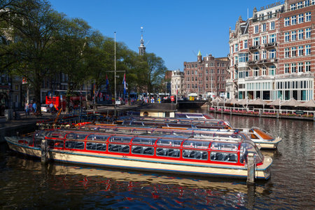 Amsterdam, Netherlands - August 27 2017: Riverboats moored on a canal opposite Muntplein square.のeditorial素材