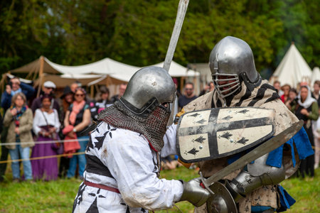 Two men in medieval armor fighting during a buhurt demonstration in Locronan, France.
