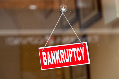 Red sign hanging at the glass door of a shop with written in it "Bankruptcy".の写真素材