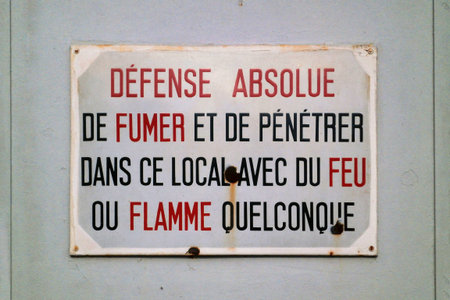 Sign saying in French "DÃ©fense absolue de fumer et de pÃ©nÃ©trer dans ce local avec du feu ou flamme quelconque", meaning in English "No smoking and no entry into this room with any fire or flame".の写真素材