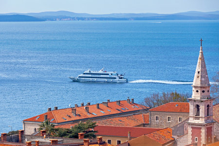 Zadar, Croatia - April 15 2019: Bell tower of the St. Francis church and convent (Croatian: Convento di S. Francesco) with a ferry passing behind.のeditorial素材