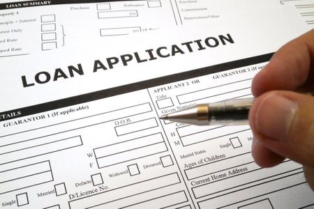 Pen hold by a fingers of somebody ready to fill a loan application form.の写真素材