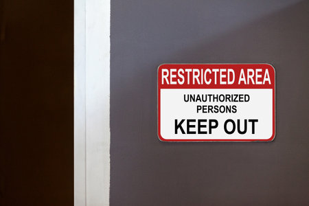 Red and white restricted area sign on the side of a corridor stating : Restricted Area, Unauthorized persons keep out.の写真素材