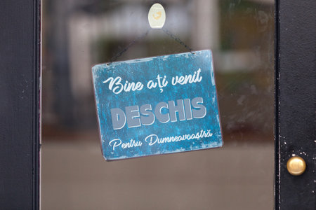 Blue open sign with written in it in Romanian: "Bine aÈi venit! DESCHIS Pentru DumneavoastrÄ.", meaning in English "Welcome! OPEN For you.".の写真素材
