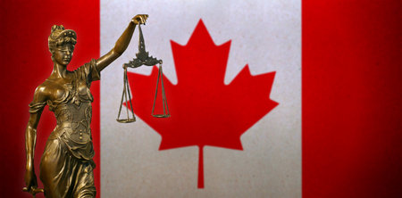 Close-up of a small bronze statuette of Lady Justice before a Canadian flag.の写真素材