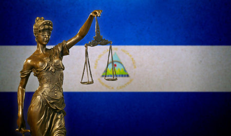 Close-up of a small bronze statuette of Lady Justice before a flag of Nicaragua.の写真素材