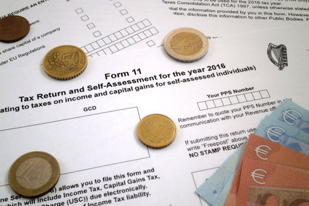 Some euro coins and banknotes on the top of an Irish tax return form (Form 11).