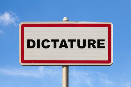 A French entry city sign against a blue sky with written in the middle in French "Dictature", meaning "Dictatorship" in English.の写真素材