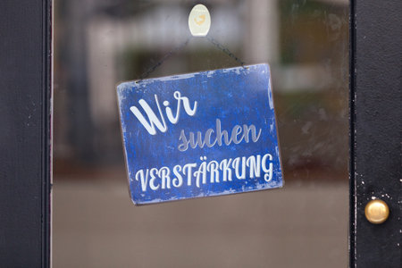 Red open sign with written in it in German: "Wir suchen VerstÃ¤rkung", meaning in English "We are looking for reinforcement".の写真素材