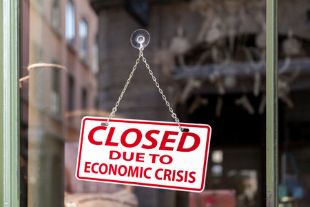 Close-up on a red and white sign in a window with written in it "Closed due to economic crisis".の写真素材