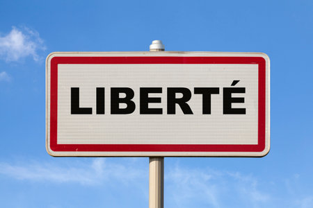 A French entry city sign against a blue sky with written in the middle in French "LibertÃ©", meaning in English "Freedom".の写真素材