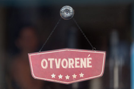 Old fashioned sign in the window of a shop saying in Slovak OtvorenÃ©, meaning in English Open.
