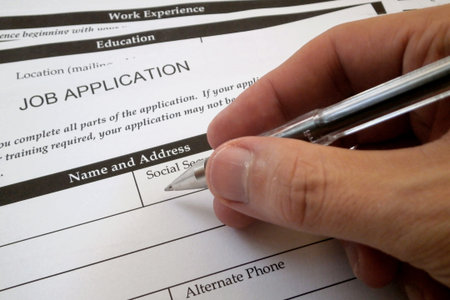 Ballpoint pen hold in the hand of a man filling a job application form.