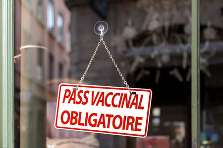 Close-up on a red and white sign in a window with written in French Pass vaccinal obligatoire...