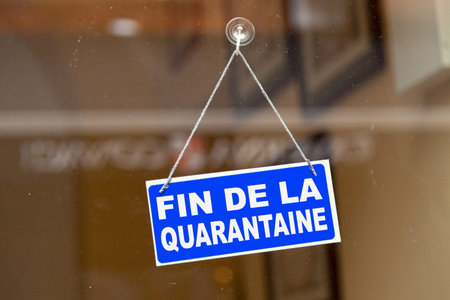 Blue sign hanging at the glass door of a shop saying in French Fin de la quarantaine meaning in...