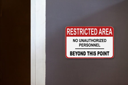 Red and white restricted area sign on the side of an open door stating : Restricted Area, No unauthorized personnel beyond this point.の写真素材