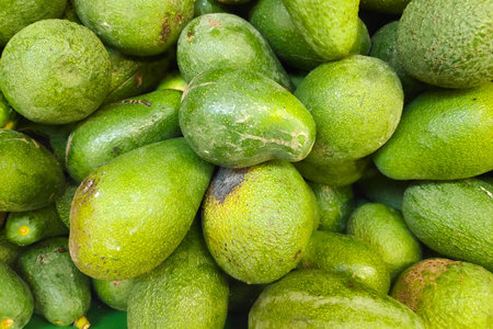 Close-up on a stack of avocados for sale on a market stall.