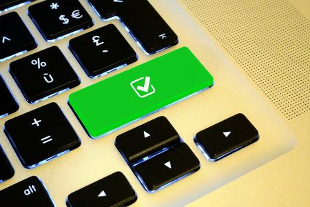 Green computer key with a white checkbox ticked shape on it. Ideal image for success themes.の写真素材