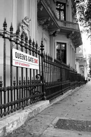 Colored street plate of Queen's Gate in London on black and white background.