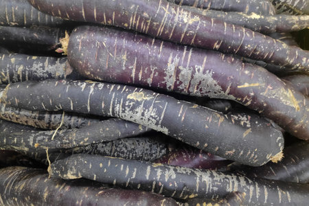 Close-up on a stack of black carrots on a market stall.の写真素材