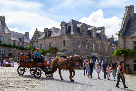 Locronan, France - August 17 2023: Horse-drawn carriage taking tourists through the city center.のeditorial素材