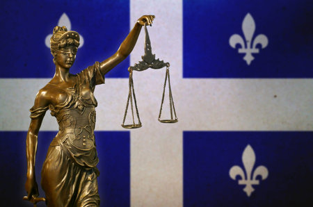 Close-up of a small bronze statuette of Lady Justice before a flag of Quebec (Canada).の写真素材
